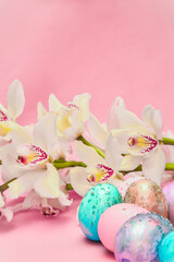 Obraz na płótnie Canvas Easter eggs and orchid flower on a pink backdrop. Happy easter food and decorations, Orthodox easter celebration, spring theme, happy easter festive food 
