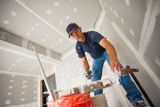Drywall worker adding drywall mud to his banjo