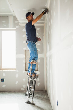 Drywall worker on stilts working on drywall joints