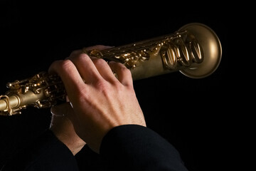 soprano saxophone in the hands of a guy on a black background