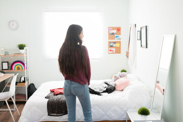 Cute teenager girl looking at her outfit in her full length mirror