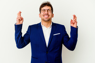 Young business caucasian man isolated on white background crossing fingers for having luck