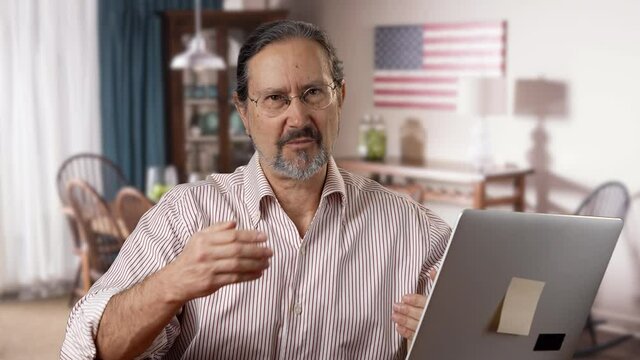 Mature man smiling looking at camera, remote presentation concept work from home. Portrait of positive man with glasses web video chat, actively gesture with hands. Front view and close-up