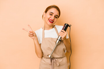 Young skinny arab cook woman joyful and carefree showing a peace symbol with fingers.
