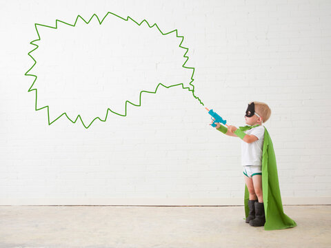 Studio shot, Portrait of boy (2-5 years) wearing green cape and holding his toy gun