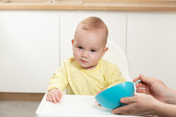 Mother Feeding Baby Sitting In Chair