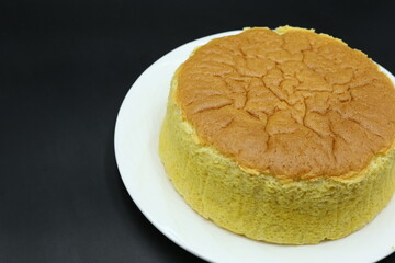 Piece of Jiggly Fluffy Japanese Cheesecake on wood Chopping board, black background, sugar, mint, straberries, woodden coat