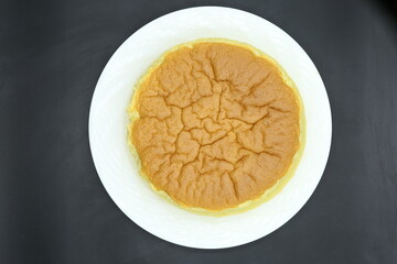 Piece of Jiggly Fluffy Japanese Cheesecake on wood Chopping board, black background, sugar, mint, straberries, woodden coat