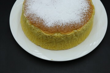 Piece of Jiggly Fluffy Japanese Cheesecake on wood Chopping board, black background, sugar, mint, straberries, woodden coat