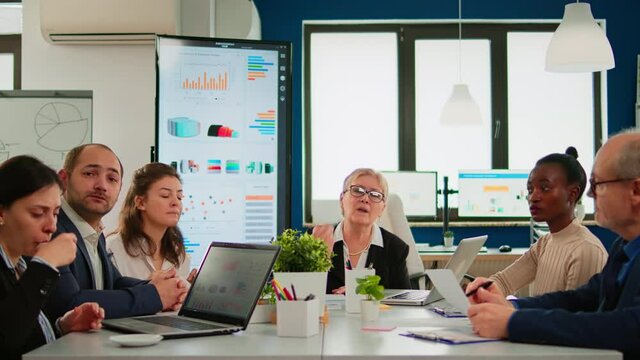 Group of diverse business people discussing with partners on video call during video meeting sitting in conference room. Internet conference call technology talk with investors, corporate