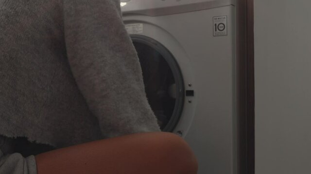Woman doing laundry loading washing machine at home