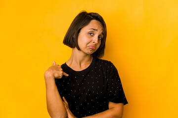 Young hispanic woman isolated on yellow person pointing by hand to a shirt copy space, proud and confident