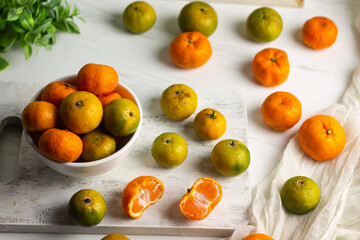 Jeruk Santang or Santang Mandarin oranges, on white bowl with white wooden background. Copy space for text. 