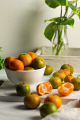 Jeruk Santang or Santang Mandarin oranges, on white bowl with white wooden background. Copy space for text. 