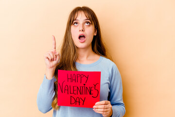 Fototapeta na wymiar Young caucasian woman holding a Happy Valentines day isolated pointing upside with opened mouth.