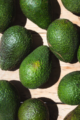 Close up shot of avocadoes in hard light on top of a vintage wooden background.
