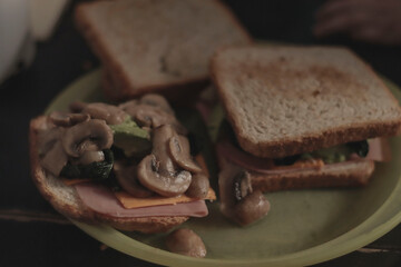 Rich sandwich breakfast with ham, yellow cheese and mushrooms.