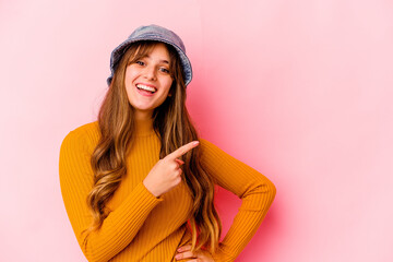 Naklejka premium Young caucasian woman wearing fishermans hat isolated smiling and pointing aside, showing something at blank space.