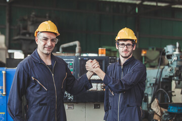 male workers and protective uniform shaking hands while working success teamwork collaboration. Two colleagues at a factory