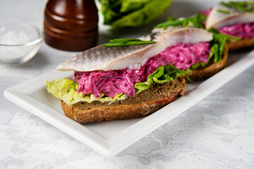 Delicious sandwiches with herring, beetroot and green salad leaves. Herring is a source of omega 3 fats. Healthy for brain and mental clarity. Brain foods concept. Home comfort cooking