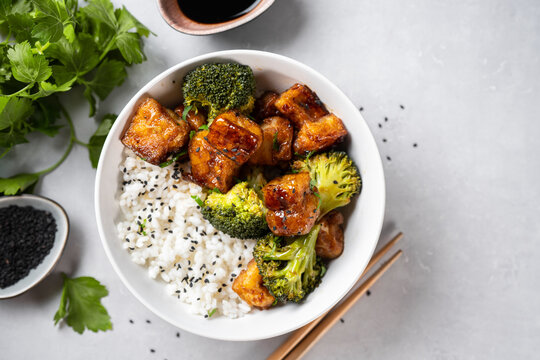 Top view of healthy tofu bowl with broccoli and rice on white background. Vegetarian food concept