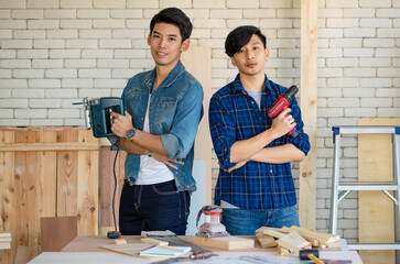 Two good looking Asian carpenter working together for DIY jobs in carpenter room with several kinds...