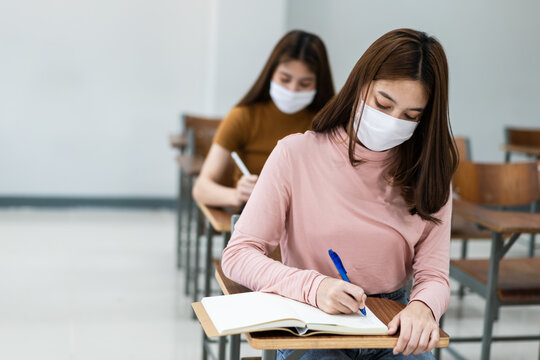 Group of college students wearing a face mask and keep distance while studying in the classroom and college or university campus to prevent COVID-19 pandemic. The new college or university campus life