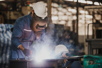 Industrial Worker at the factory welding. Workers wearing industrial uniforms and Welded Iron Mask...