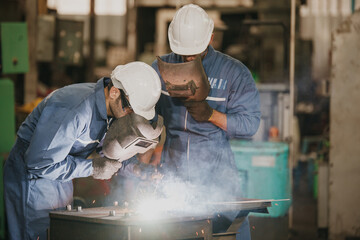 Industrial Worker at the factory welding. Workers wearing industrial uniforms and Welded Iron Mask...