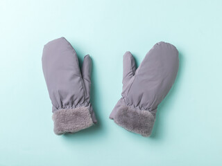 Grey warm women's mittens on a blue background.