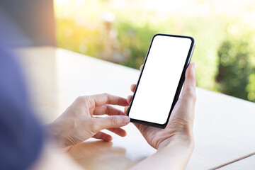 cell phone blank white screen mockup.woman hand holding texting using mobile on desk at...