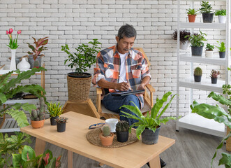 A goold looking senior Asian man wearing eyesglasses sitting and drink coffee and reading the newspaper with happiness. Idea for relaxing and slowly life of older people after retirement