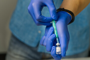 doctor dials the vaccine into a syringe. a nurse with a vaccine and a syringe in her hands