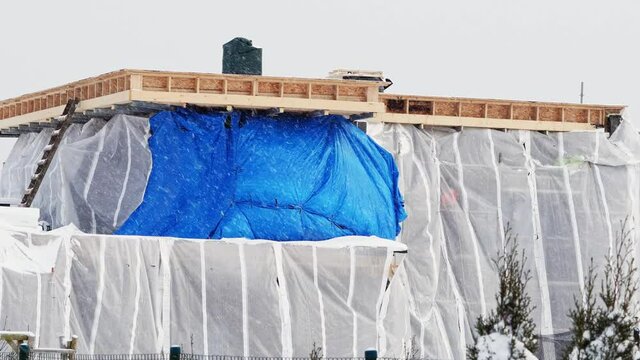 private house construction site wrapped in foil to protect against bad weather in winter.