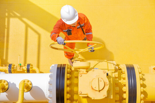 Production operator opening ball valve on offshore oil and gas production platform.