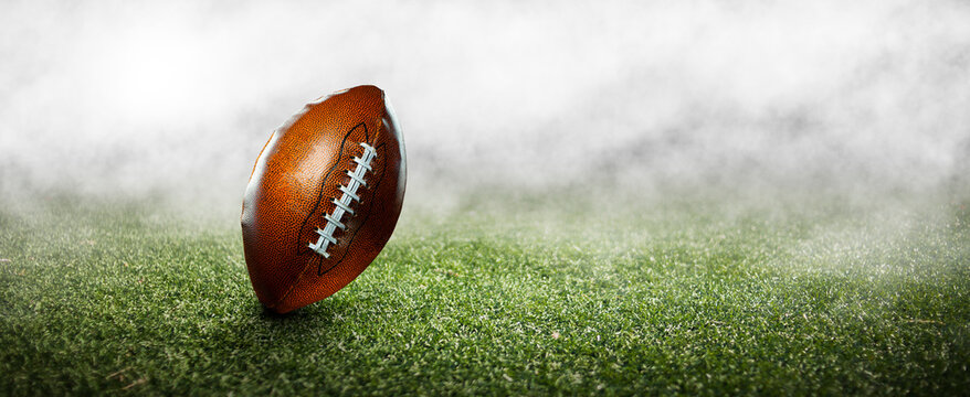 American football ball on the grass of a stadium