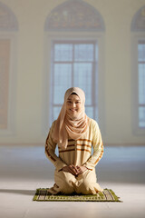 Portrait of a young and beautiful Muslim woman in hijab dress sitting in the mosque