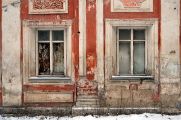 Vintage background with the texture of an old painted concrete wall with windows. Elements of the architectural decor of the building.