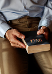 Christian man is sitting and opening a Bible. In order to pray before Jesus remember His goodness....