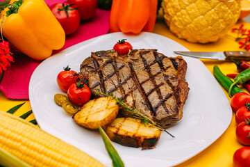 t-bone steak with grilled vegetables on a decorated table