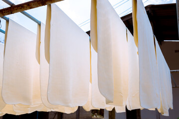 The farmer making rubber sheets hang on bamboo process dry by solar energy . A raw rubber latex flat to dry. Rubber sheet is a raw material for many industrial product. 