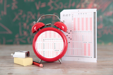 Abstract alarm clock and test answer card in front of blackboard