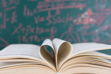 Love folded from an open book in front of the blackboard