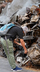 Woman tourist take a photo heap of old machine parts in second hand machinery shop