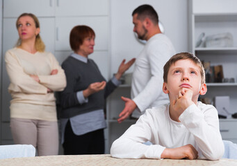 Sad desperate little boy during parents quarrel in home interior.