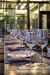 Modern veranda restaurant interior, banquet setting, glasses, plates