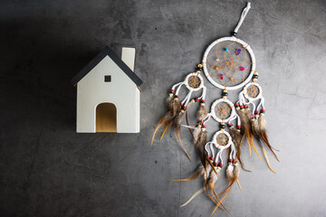 Dreamcatcher and wooden house on Gray-black cement floor background with copy space.Concept to protect the house from evil and bad luck.