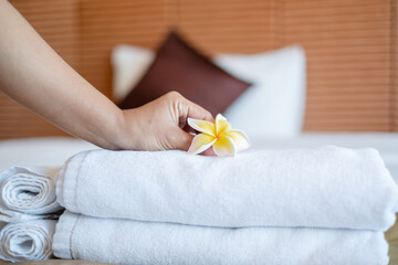 Obraz na płótnie Canvas A hotel maid stacked towels on the bed and placed flowers on the towels in a hotel room