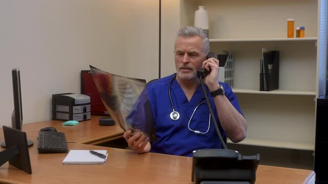 Male doctor on phone discussing patient x-ray with colleague