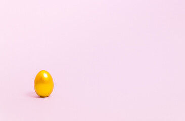 Easter egg decorated with gold paint on a pink background. Concept for Easter, spring. Selective focus. Copy space.